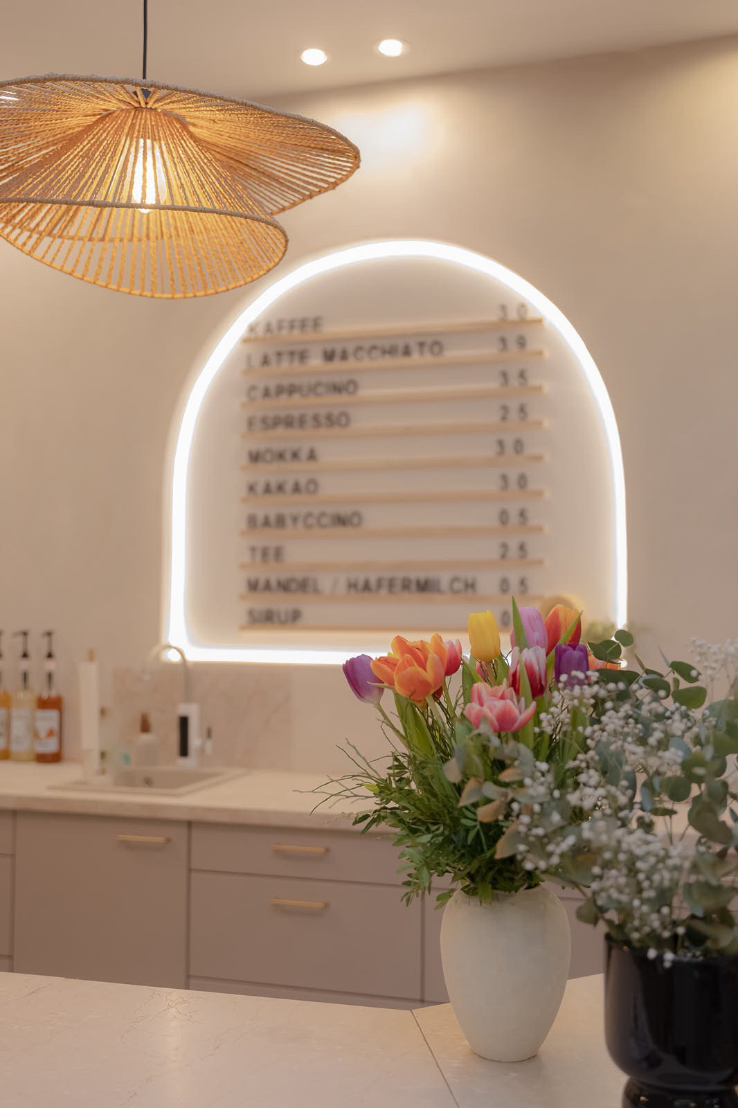 Barista-Bar mit beleuchteter Preistafel und frischen Tulpen im Little Moon